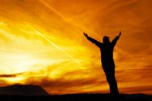 Person raising arms towards sunrise